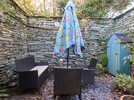 A garden seating area with a colorful umbrella at Buttonhole Cottage Ambleside