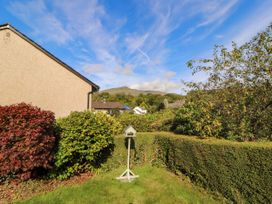A garden with hedges and a bird feeder at Sunbeam Cottage Coniston