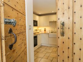 A kitchen with an oven and sink visible through a wooden door at Chapel How in Ambleside