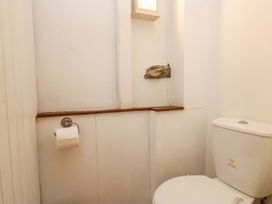 A bathroom with a toilet and wooden shelf at Chapel How in Ambleside
