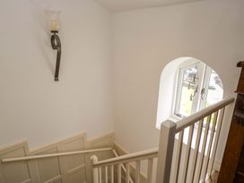 A staircase with a wall sconce and a window at Chapel How, Ambleside