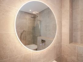A bathroom with a round mirror and shower at Chapel How in Ambleside