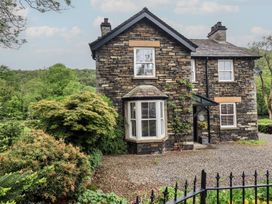 A house with a stone exterior and windows at Newby Bridge House in Newby Bridge