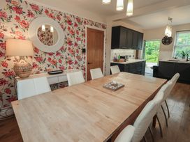 A dining room with a wooden table and white chairs at Newby Bridge House in Newby Bridge