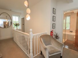 A hallway with a staircase and armchair at Newby Bridge House, Newby Bridge