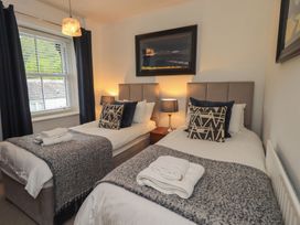 A bedroom with two beds and a lamp at Newby Bridge House in Newby Bridge