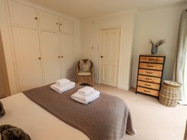 A bedroom with a bed, towels, wardrobe, and chair at Underheron in Grasmere