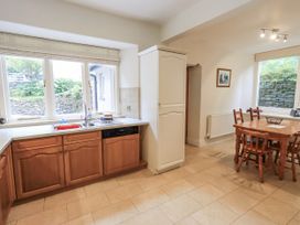 A kitchen with wooden cabinets and a dining table at Miyanli in Bowness