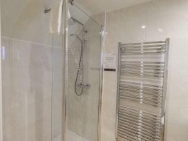 A shower with glass doors and a towel rack at Miyanli in Bowness