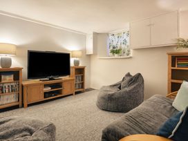 A living room with a television and shelves at Herdwick Cottage Ambleside