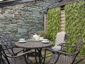 A garden with a stone wall and table set with teapot and cups at Herdwick Cottage Ambleside
