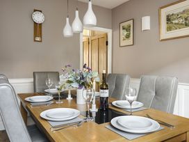 A dining room with a table set and a wine bottle at Herdwick Cottage Ambleside