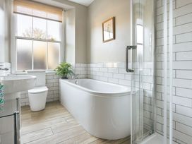 A bathroom with a bathtub, shower, and sink at Herdwick Cottage Ambleside