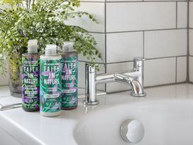 A bathroom with shampoo, conditioner, and body wash at Herdwick Cottage Ambleside