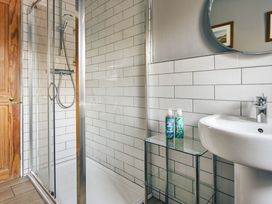 A bathroom with a shower, sink, and mirror at Herdwick Cottage Ambleside