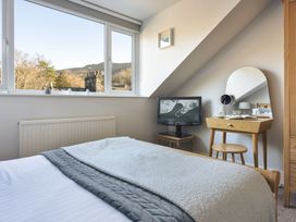 A bedroom with a bed, television, and table at Herdwick Cottage Ambleside