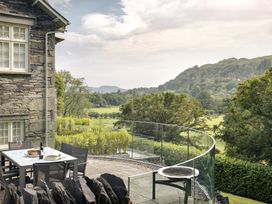 An outdoor patio with a table and chairs overlooking a landscape at Take Five in Ambleside