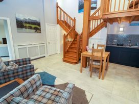 A living room with a staircase and dining area at Cragfell Cottage in Cartmel Fell