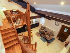 A living room with a staircase and seating area at Cragfell Cottage in Cartmel Fell