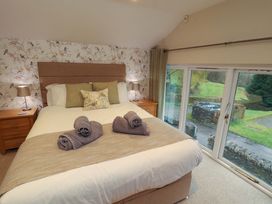 A bedroom with a bed and view of the outside at Cragfell Cottage in Cartmel Fell