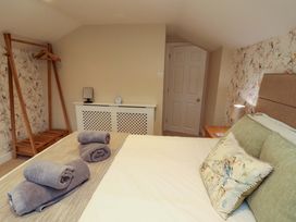 A bedroom with a bed, towels, and a clothes rack at Cragfell Cottage in Cartmel Fell