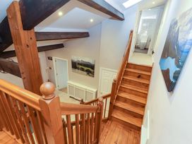 A staircase with wooden railing leading to a hallway at Cragfell Cottage in Cartmel Fell