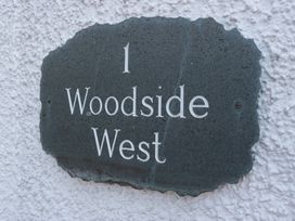 A property sign with number and name at Woodside West in Bowness