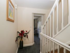 A hallway with a flower vase and staircase at Woodside West in Bowness