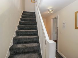 A staircase with a handrail and light fixture at Woodside West in Bowness