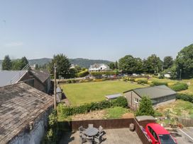 A garden with a parking area and table and chairs at Woodside West in Bowness