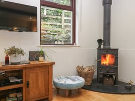 A living room with a wood stove and television at Corner Cottage in Troutbeck