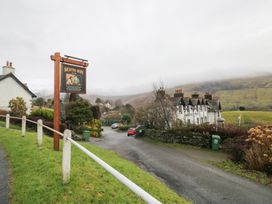 A sign for Mortal Man with buildings and a road in Troutbeck