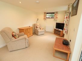 A living room with two recliners and a TV stand at Rowanberry Cottage in Grasmere