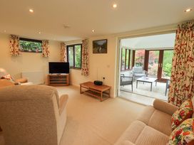 A living room with a sofa, armchair, and television at Rowanberry Cottage in Grasmere