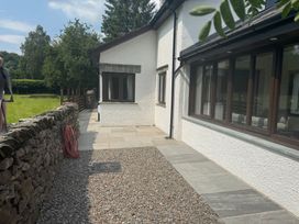 An outdoor view of a house with a patio and stone wall at Rowanberry Cottage in Grasmere