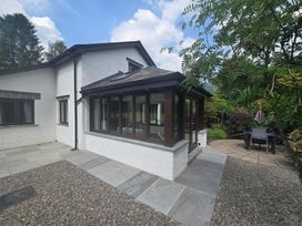 A garden with a conservatory and outdoor seating at Rowanberry Cottage in Grasmere