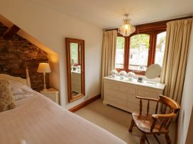 A bedroom with a bed, mirror, lamp, and dresser at High Raise in Grasmere