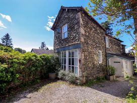 A stone house with windows and bushes at Tower Cottage in Windermere