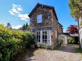 A stone house with windows and a door surrounded by bushes at Tower Cottage in Windermere