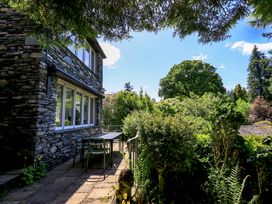 A garden with a stone wall, table, and chairs at Tower Cottage in Windermere