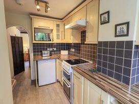 A kitchen with cabinets, stove and sink at Smithy Cottage at Bowland Bridge in Bowness