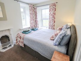A bedroom with a bed and windows at Smithy Cottage at Bowland Bridge, Bowness