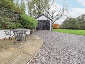 An outdoor area with a table, chairs, and a garage at Smithy Cottage at Bowland Bridge, Bowness