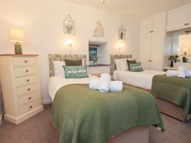 A bedroom with two beds and a lamp at Fairfield Cottage in Grasmere