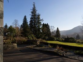 A garden with trees and mountains at Fairfield Cottage in Grasmere