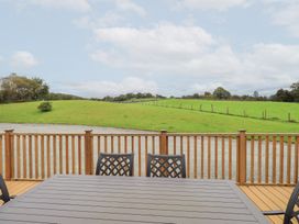An outdoor area with a wooden table and chairs overlooking grassland at The Loghey in Hawkshead