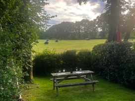 A picnic table set with glasses and a bottle in a garden at Barn Cottage, Bassenthwaite, near Keswick