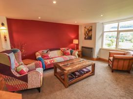 A living room with a sofa, coffee table, and lamp at Boxwood Cottage in Troutbeck