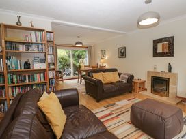 A living room with a bookshelf, sofa, and dining area at Redwood in Ambleside