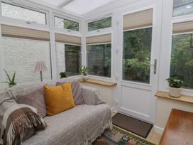 A conservatory with a sofa and plants at Redwood in Ambleside